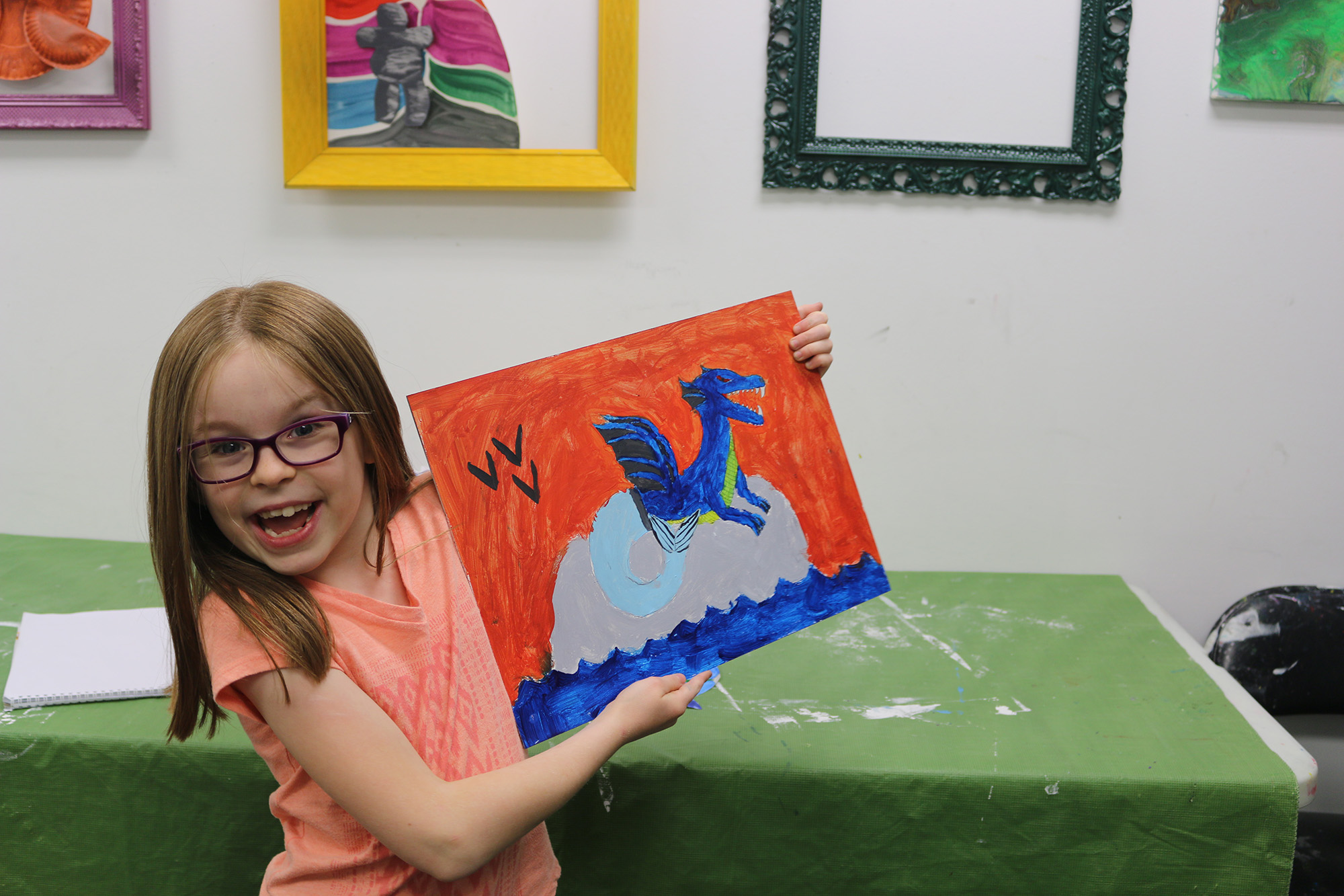 A little girl at summer art camp showing off her painting.