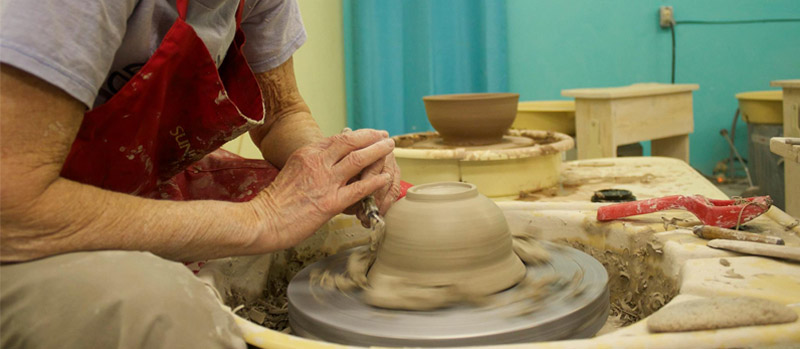 A pottery student throwing a bowl on the potters wheel.